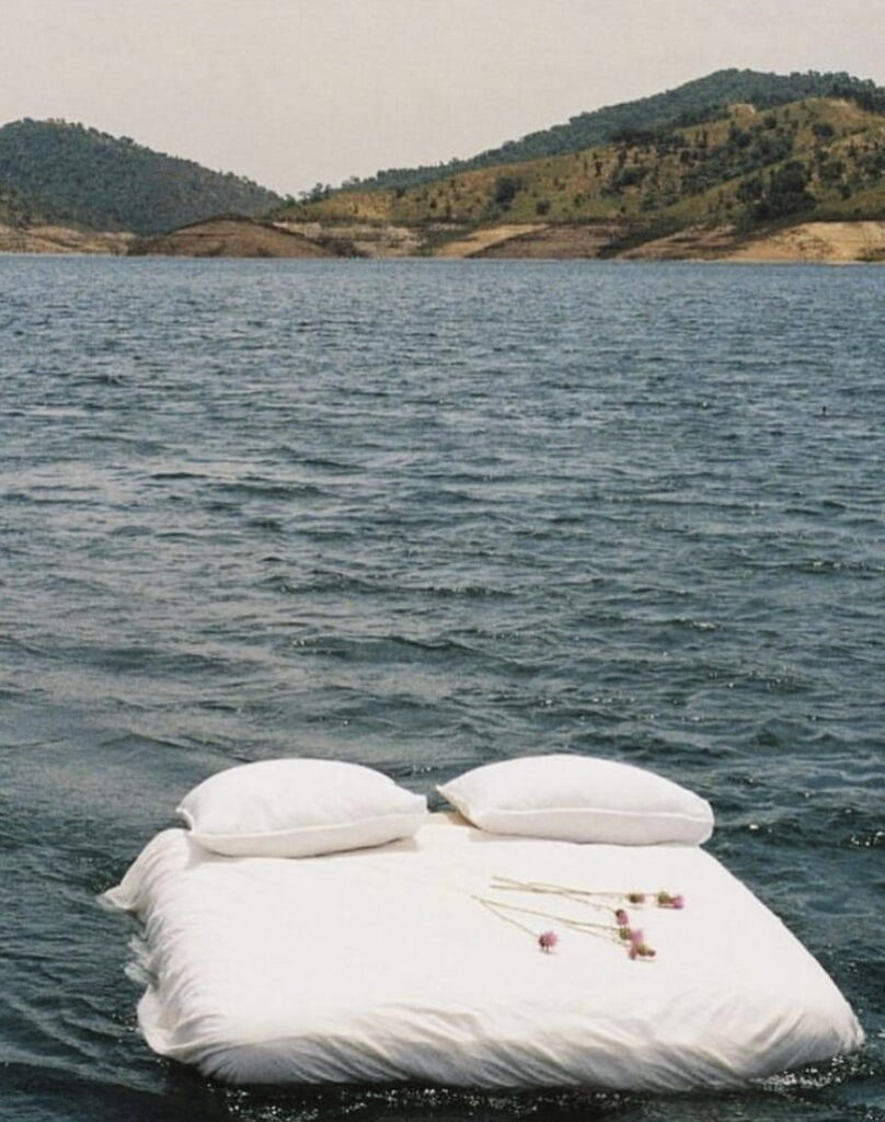 łóżko z białą pościelą i różami na wodzie